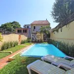Casa com aproximadamente 240m² divididos em 2 pavimentos e mais anexo. Possui no térreo: living 02 ambientes com lareira, dormitório, lavabo, sala de jantar, cozinha americana, jardim de inverno e lav