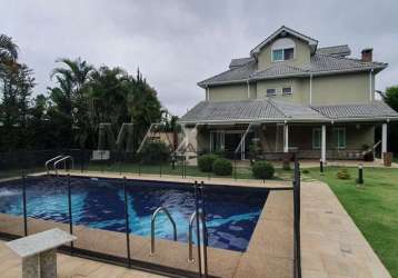 Casa de alto padrão 573m², 5 suítes, sala tv, lareira, área gourmet e piscina aquecida com cascata.