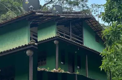 Charmosa casa à venda em meio as montanhas com vista para um sereno riacho.