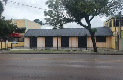 Loja com ampla frente, estacionamento, rua com grande fluxo de veículos e pedestres.