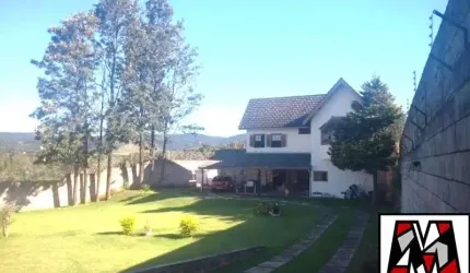 Casa com amplo quintal e gramado, tipo chalé, várias vagas de garagem.