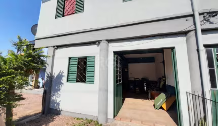 Casa comercial com duas vagas de garagem na frente, sala de recepção, sala grande aos fundos para estoque e lavabo, dois apartamentos no segundo piso, sendo um deles com um quarto, banheiro e cozinha,