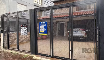 Casa à venda no bairro Menino Deus em Porto Alegre. Imóvel espaçoso e confortável, com três dormitórios, sendo uma suíte, living amplo com espaço para três ambientes, lareira, churrasqueira, banheiro 