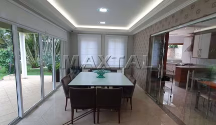 Casa de alto padrão 573m², 5 suítes, sala, TV, lareira, área gourmet e piscina aquecida com cascata.