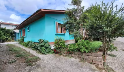 Casa em alvenaria com três quartos, sala, cozinha, banheiro,  área coberta com fogão campeiro, churrasqueira  e estacionamento na lateral. Nos fundos uma casa de madeira, com dois quartos, sala e cozi
