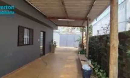 Casa com 3 quartos, cozinha, área de serviço e banheiro externo, piso em cerâmica, telhado caixote, corredor lateral, área verde e quadra de areia no fundo do quintal.