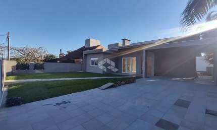 Casa térrea com 4 suítes + lavabo, amplo living com lareira e com acesso ao pátio em frente, quanto aos fundos da casa, em Atlântida/RS.
