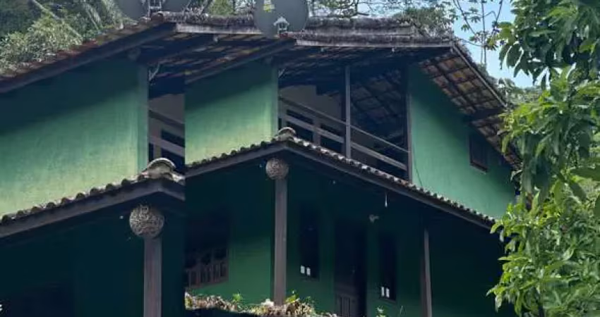 Charmosa casa à venda em meio as montanhas com vista para um sereno riacho.