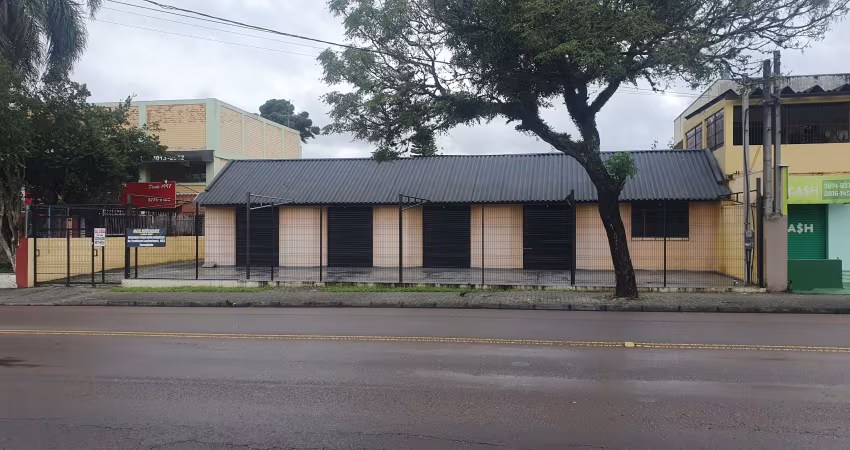 Loja com ampla frente, estacionamento, rua com grande fluxo de veículos e pedestres.